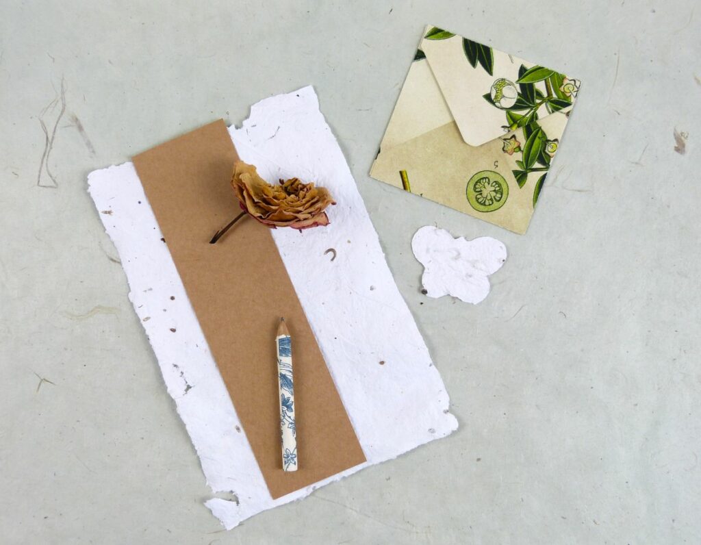ein Blatt selbst gemachtes Samenpapier mit Umschlag und Schmetterlingsform